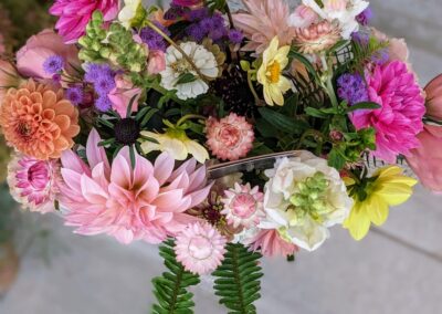 Bird's eye view of pink, purple, yellow, and white flowers in a vase.