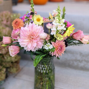 Colorful flowers in a vase on a concrete step.