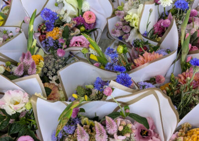 Pink, yellow, white, and purple flower arrangements wrapped in white paper.