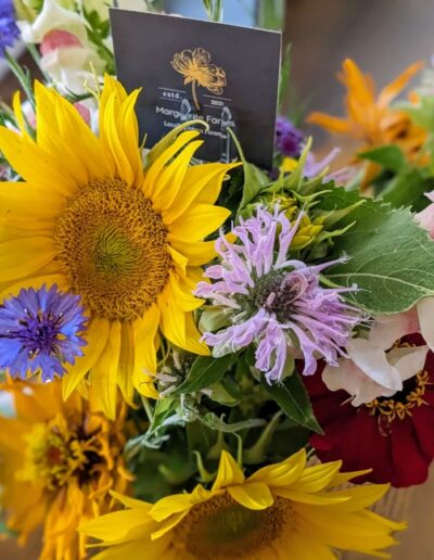 A summery bouquet featuring sunflowers and purple wildflowers.