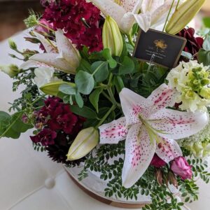 A floral arrangement featuring an assortment of white lilies and red flowers.