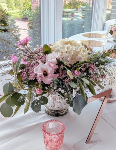 Pink and white flowers in a vase at a table for a wedding reception with the number 7 on it.