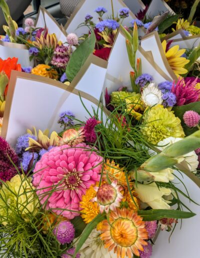 Multiple bouquets of colorful flowers wrapped in white paper.