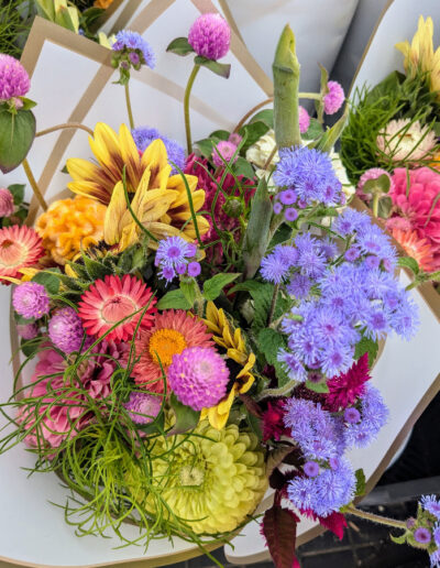 A bouquet of various colorful flowers wrapped in white paper.