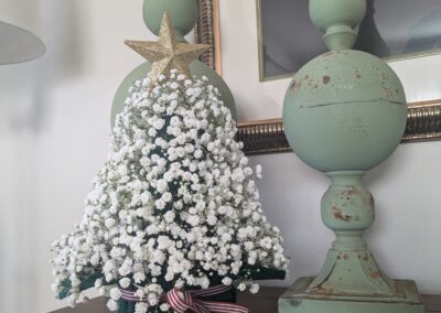 A small Christmas tree made of baby's breath sitting on a mantle.